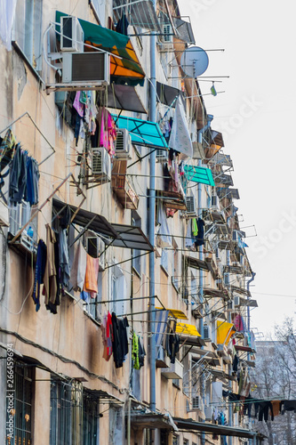 Photo of the facade of a high-rise building in a poor neighborhood with lots of clothes drying out right outside the windows