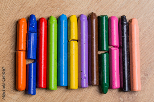 Many colourful used crayon in a row isolated on a wooden surface