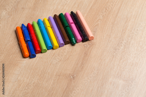 Colourful crayons in a row for painting on a wooden surface
