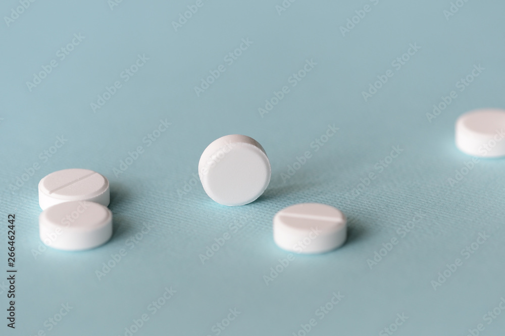 White tablets scattered on a blue background close up White tablets scattered on a blue background close up