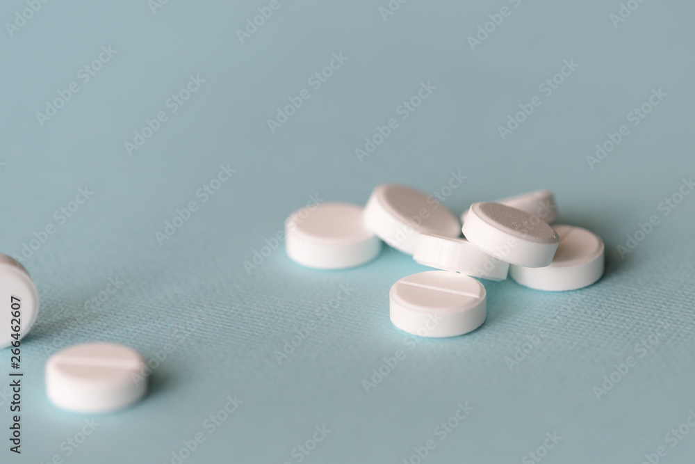 White tablets scattered on a blue background close up White tablets scattered on a blue background close up