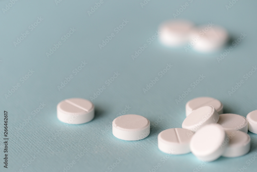 White tablets scattered on a blue background close up White tablets scattered on a blue background close up