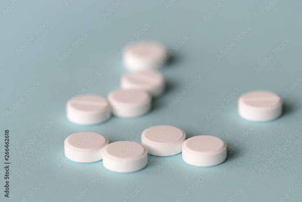 White tablets scattered on a blue background close up White tablets scattered on a blue background close up
