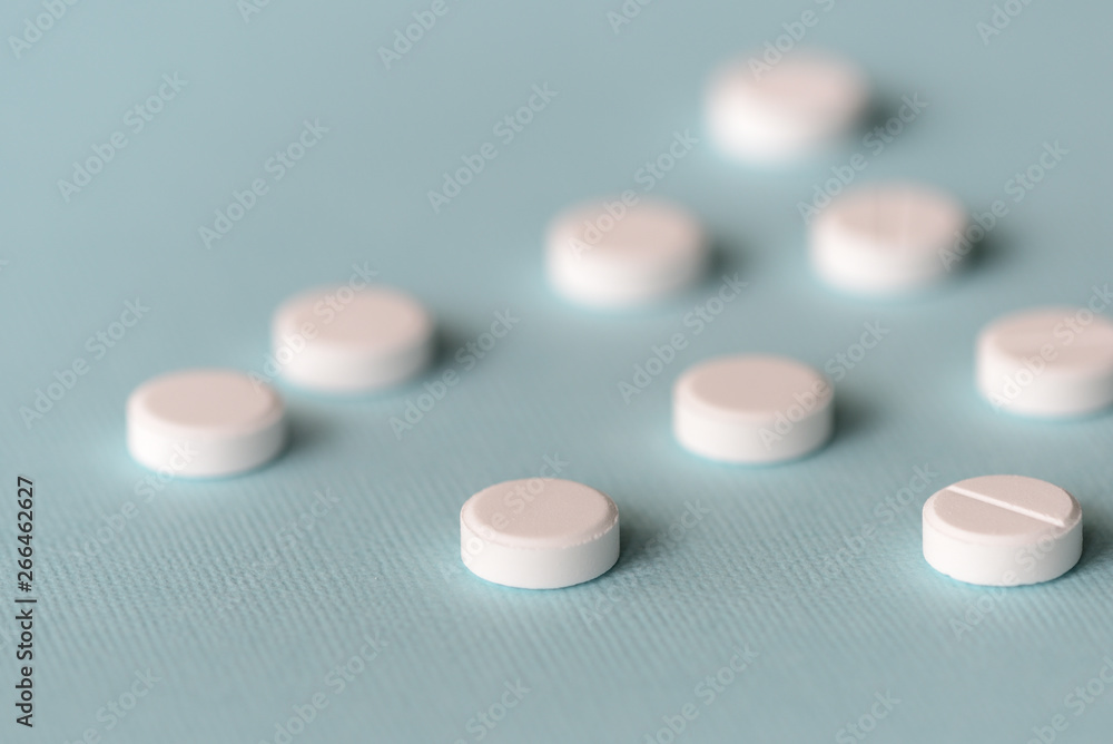 White tablets scattered on a blue background close up White tablets scattered on a blue background close up