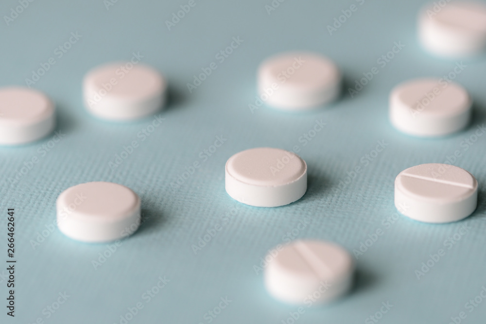 White tablets scattered on a blue background close up White tablets scattered on a blue background close up