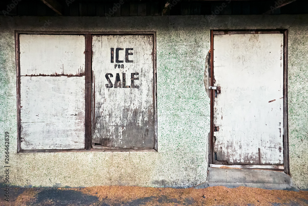 Facade of a rundown shop with closed wooden window and door at the market in Leon, Iloilo province, Philippines. Ice for sale is written on the window