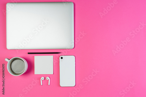 Laptop Phone Coffee on Pink Workspace Flat Lay with Copy Space. White Smartphone, Earphone and Pencil on Minimal Clear Layout Background with Paper Note. Business Workspace Order Inspiration Concept