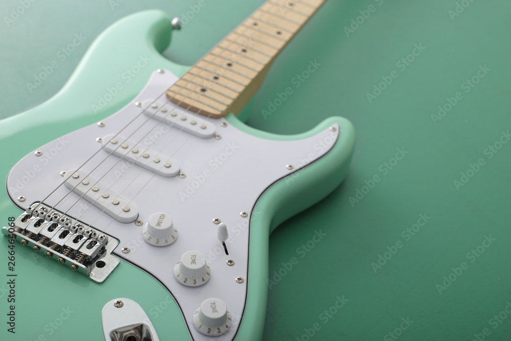 緑色の背景に置いたパステル緑色のエレキギターストラトキャスター