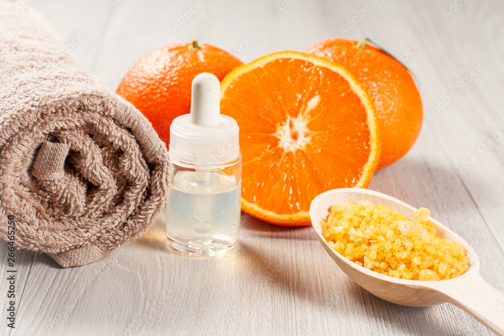 Cut orange with two whole oranges, towel, bottle with aromatherapy oil and wooden spoon with yellow sea salt. Cut orange with two whole oranges, towel, bottle with aromatherapy oil and wooden spoon with yellow sea salt.