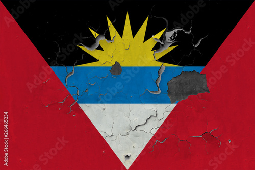 Close up grungy, damaged and weathered Antigua and Barbuda flag on wall peeling off paint to see inside surface. photo