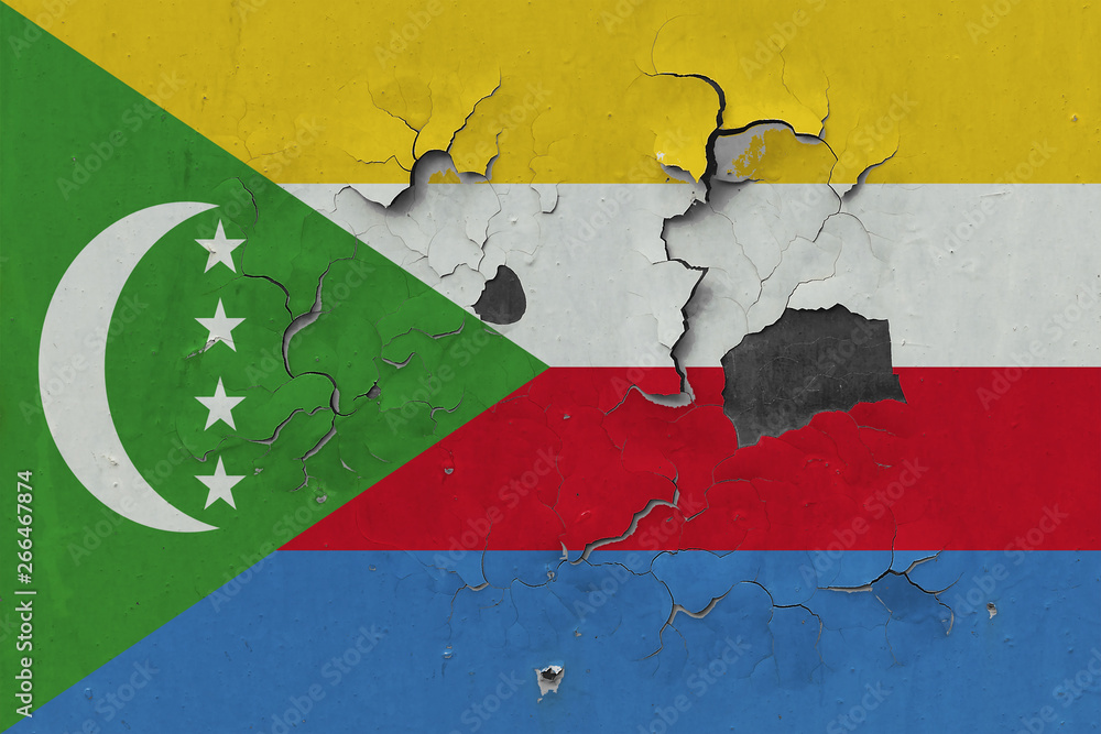 Close up grungy, damaged and weathered Comoros flag on wall peeling off paint to see inside surface.