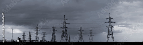 Power station in the steppe.Power lines and sky with clouds.High voltage power lines.Field and aerial lines, silhouettes at dusk.Electric power industry and nature concept.In black and white.