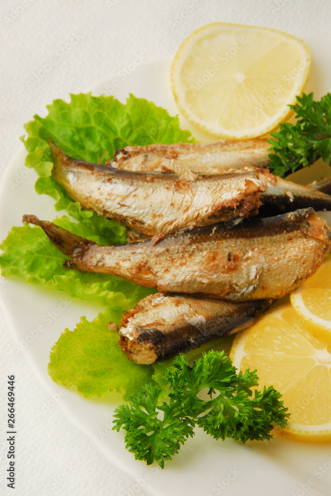 Pan-fried spiced sprats with lemon, salad on a plate Pan-fried spiced sprats with lemon, salad on a plate