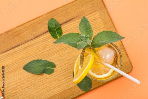 Cold refreshing summer lemonade with ice and lemon slices  decorated with mint leaves in a tall glass.