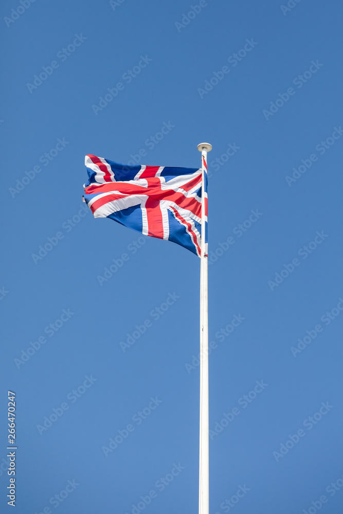 British flag on a mast, cloudy sky in background British flag on a mast, cloudy sky in background