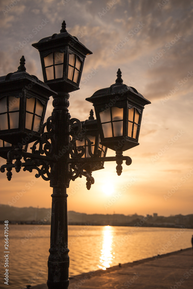 poetic vintage streetlight in a sunset in front of the sea