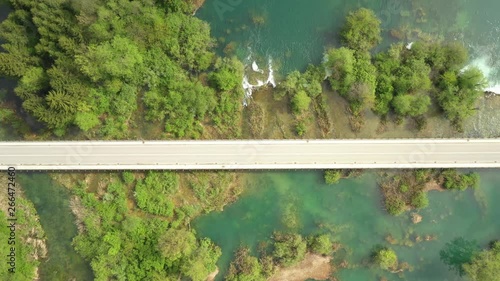 Sar crossing road bridge over Mreznica river in Croatia, overhead shot of countryside landscape, waterfalls and trees in spring photo