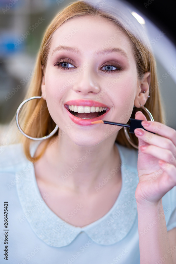 Nice young woman using a shiny lipgloss Nice young woman using a shiny lipgloss