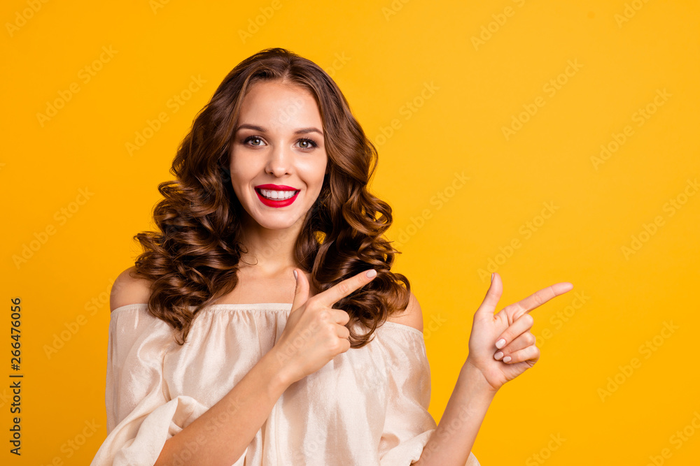 Obraz premium Close-up portrait of her she nice attractive lovely cheerful cheery positive wavy-haired lady pointing two forefingers aside ad new novelty isolated over bright vivid shine yellow background
