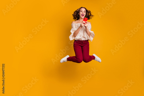 Full length body size view portrait of nice attractive slim fit thin glad cheerful cheery wavy-haired lady using modern technology device gadget isolated over bright vivid shine yellow background