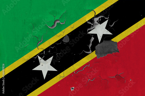 Close up grungy, damaged and weathered Saint Kitts And Nevis flag on wall peeling off paint to see inside surface. photo