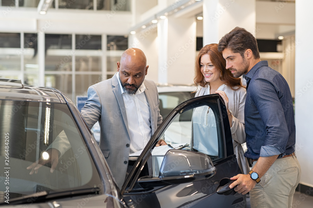 Salesman showing car features to couple