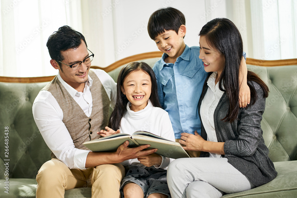 asian mother and father and two children reading book together asian mother and father and two children reading book together