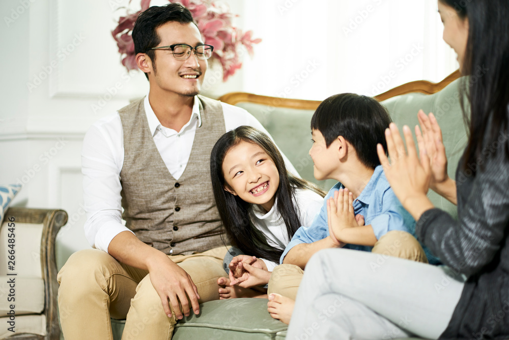 asian mother and father and two children chatting at home asian mother and father and two children chatting at home