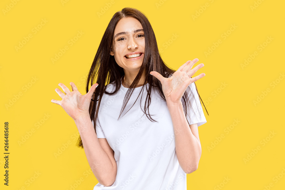Happy smiling and surprised girl. Beautiful female half-length portrait isolated on yellow studio background. Young smiling woman. Negative space. Facial expression, human emotions concept. Happy smiling and surprised girl. Beautiful female half-length portrait isolated on yellow studio background. Young smiling woman. Negative space. Facial expression, human emotions concept.