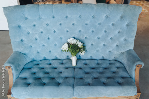 A bridal bouquet of white eustomas lies on a blue sofa in a modern studio. Wedding details. Photography and portrait. photo