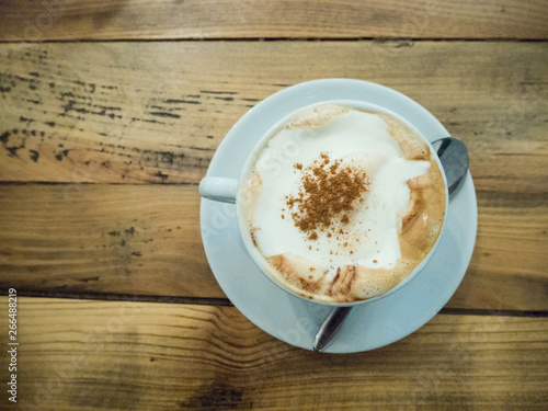 Cup of cappuccino coffee on a wooden background
