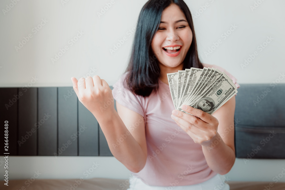 Attractive Woman in Happy Expressions After Withdraw Money Cash From Money Savings Investment While Holding Dollars on Her Bedroom. Business Financial Investing and Savings Interest Attractive Woman in Happy Expressions After Withdraw Money Cash From Money Savings Investment While Holding Dollars on Her Bedroom. Business Financial Investing and Savings Interest