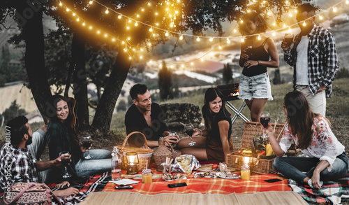 Canvas Print Happy friends having fun at bbq dinner with vintage lights outdoor drinking wine