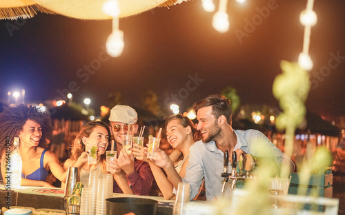 Canvas Print Happy friends cheering and drinking cocktails at beach party outdoor - Young mil