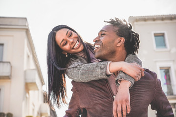 African couple having fun outdoor in city tour - Young people lovers enjoying time together during vacation journey - Love, fashion, travel and relationship concept - Focus on man face