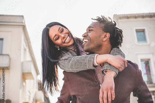 African couple having fun outdoor in city tour - Young people lovers enjoying time together during vacation journey - Love, fashion, travel and relationship concept - Focus on man face
