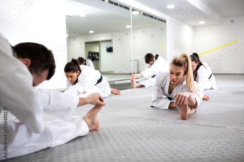 Martial artists doing leg splits while warming up for taekwondo practice