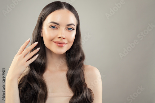 Portrait of pretty brunette woman with healthy skin and hair on gray background