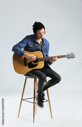 Quadro su tela Handsome young man playing guitar on white background