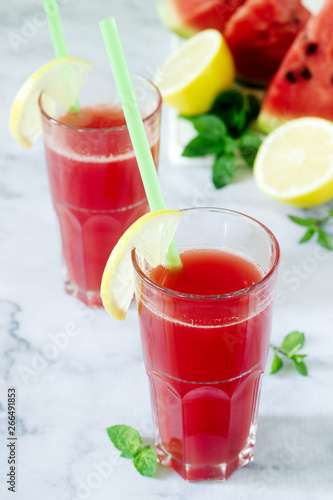 Cold watermelon lemonade with mint and lemon in glass glasses and ingredients for lemonade on a light background.