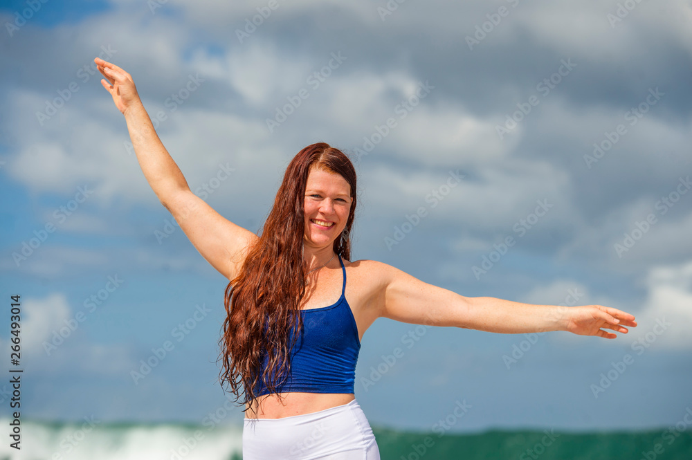 young happy and attractive red hair woman having fun standing on rock at the sea enjoying beach holidays at tropical destination isolated on blue sky young happy and attractive red hair woman having fun standing on rock at the sea enjoying beach holidays at tropical destination isolated on blue sky