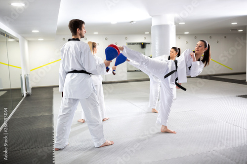 Two girls training taekwondo and kicking target pads