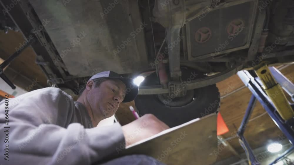 A mechanic completes data on a sheet about the maintenance of a vehicle A mechanic completes data on a sheet about the maintenance of a vehicle