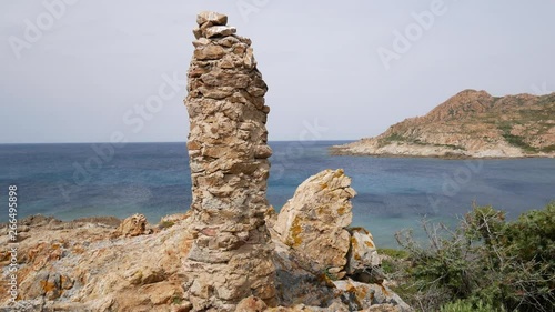 Jagged red rocks and Mediterranean scrub on the coast of the Desert des Agriates. Ostriconi beach, Balagne region, Corsica, France. photo