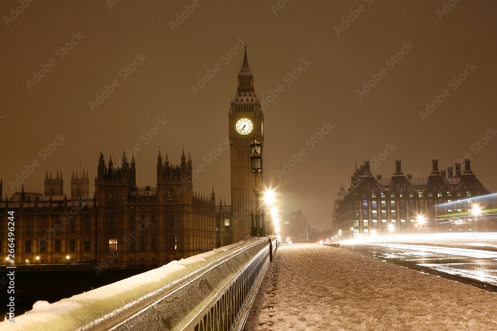 Snow covered Westminster Palace at dawn over dark grey sky.