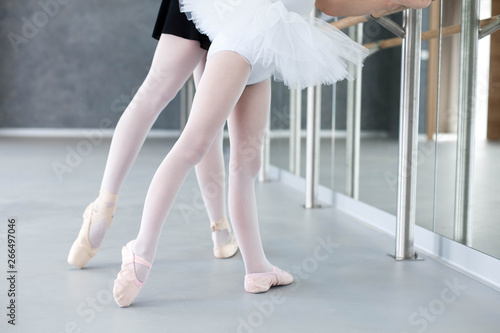 Two ballerinas child girl and woman in ballet pointe shoes. Little kid and adult teacher are studying choreographic position for legs in front of mirror in classical dance school. Close up.