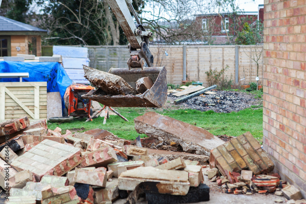 Demolition of the garage in the garden, excavator, selective focus Demolition of the garage in the garden, excavator, selective focus