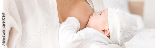 Panoramic shot of mother breastfeeding baby at home