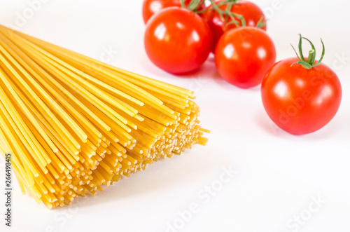 Spaghetti lie on a white background, along with cherry tomatoes