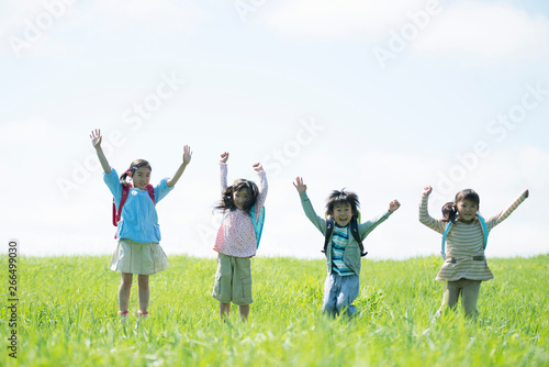 草原で両手を挙げる小学生